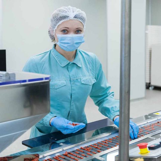 Pharmaceutical technician in sterile environment working on production of pills at pharmacy factory